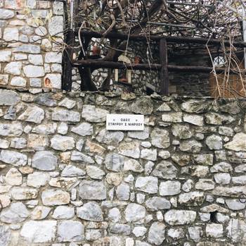Φωτογραφία από έναν πέτρινο τοίχο ο οποίος έχει μια επιγραφή η οποία γράφει ΟΔΟΣ ΣΤΑΥΡΟΣ ΝΙΑΡΧΟΣ